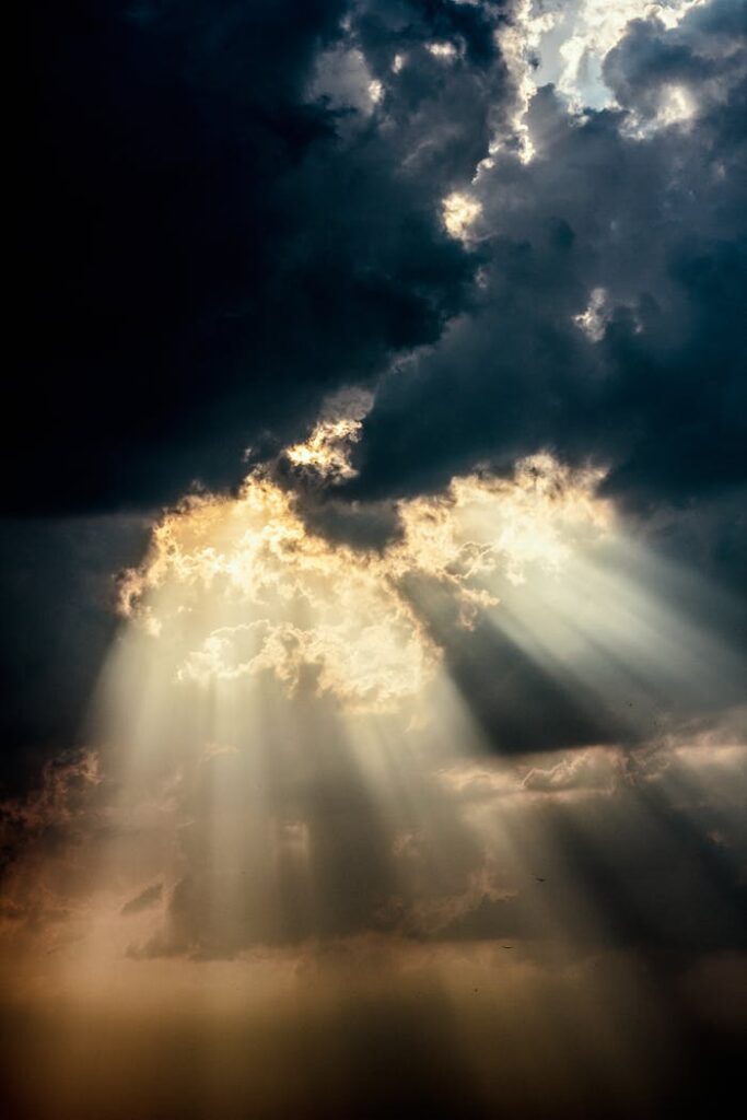 Sun rays piercing through dark clouds create a dramatic sky scene.